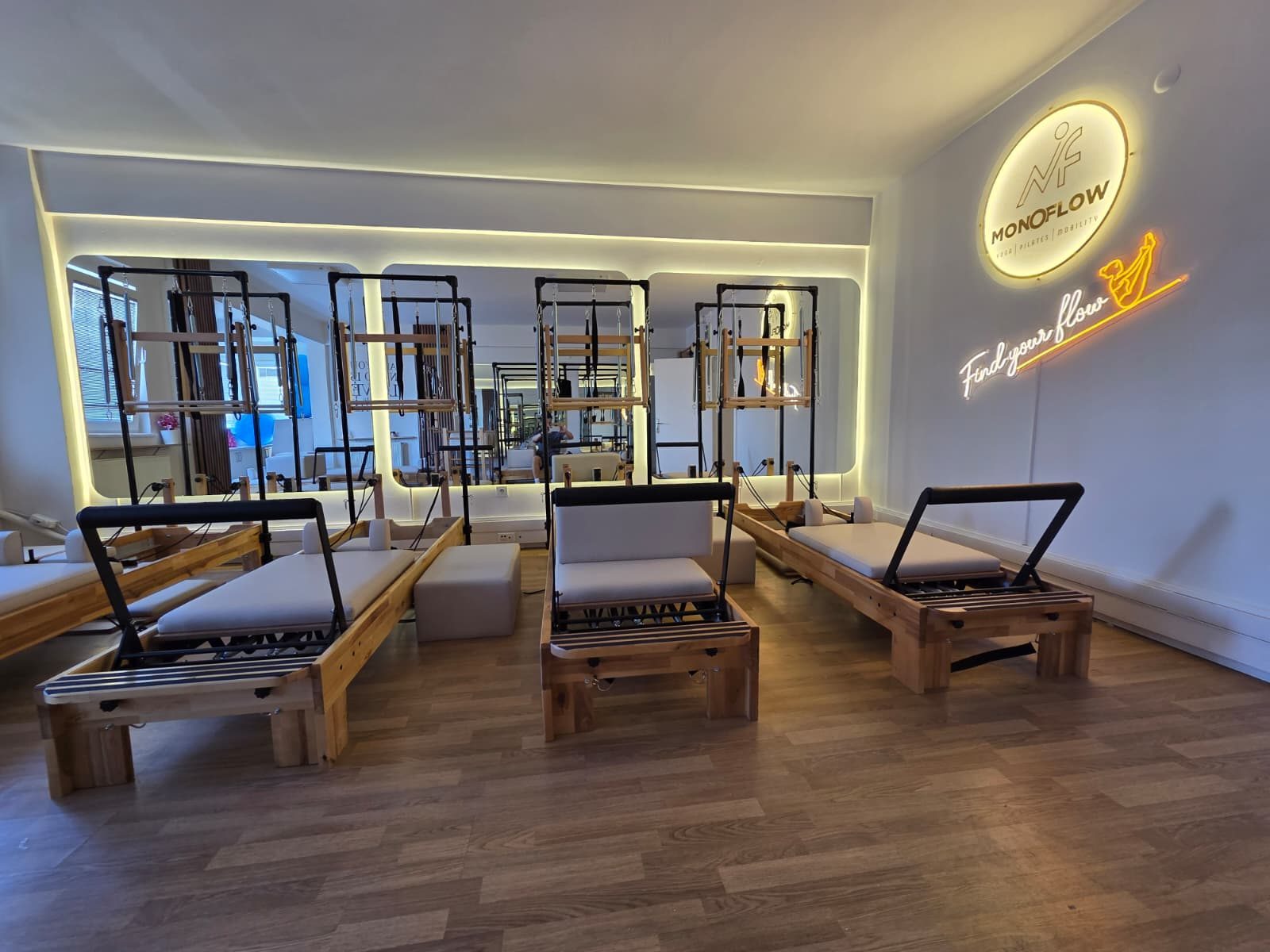 MonoFlow Kadıköy reformer pilates stüdyosu — ahşap reformer yatakları ve aydınlatmalı MonoFlow logosu